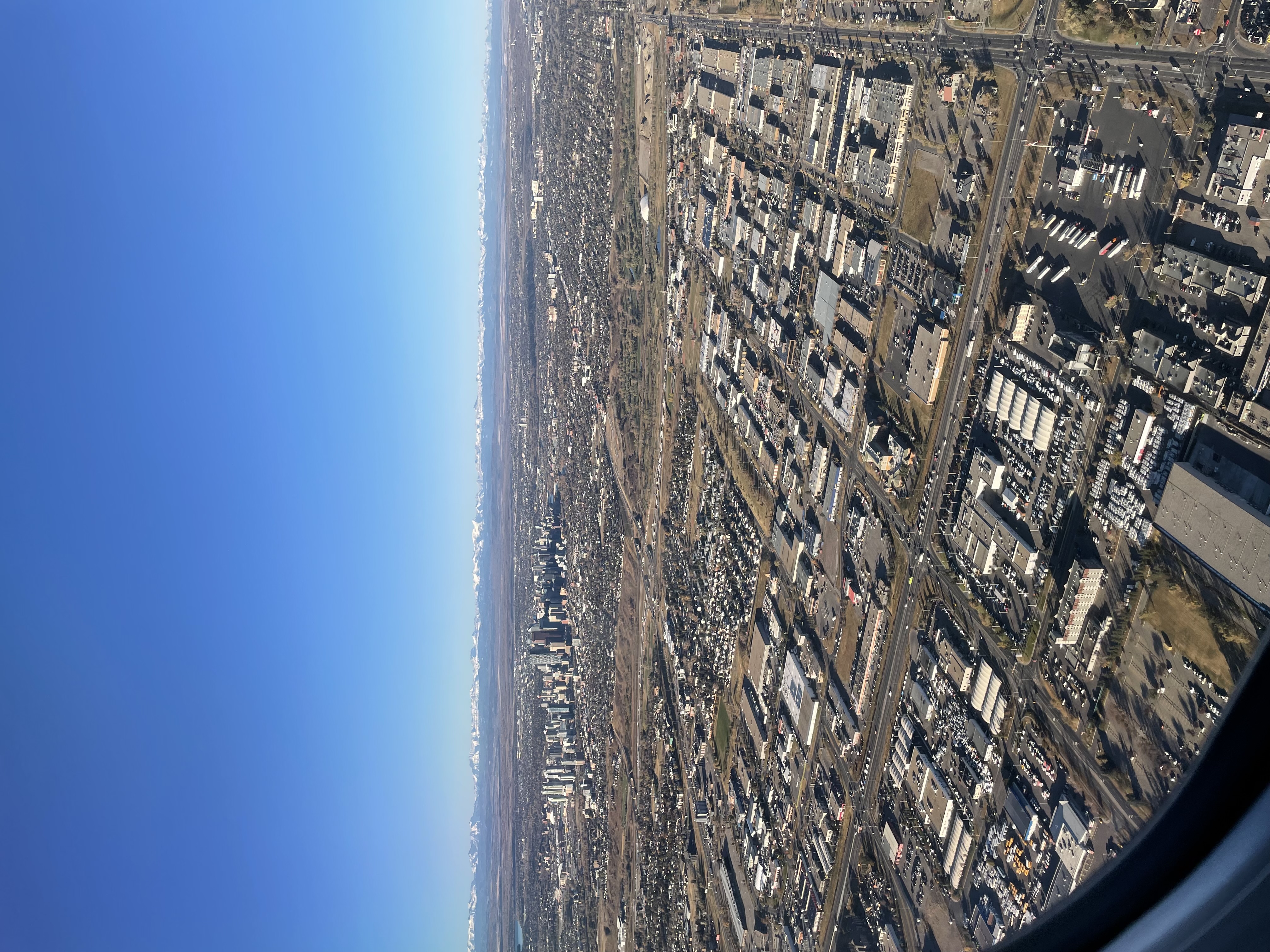 View of Calgary during takeoff, heading south.   Snow capped mountains in the far distance, and a downtown core for ants.