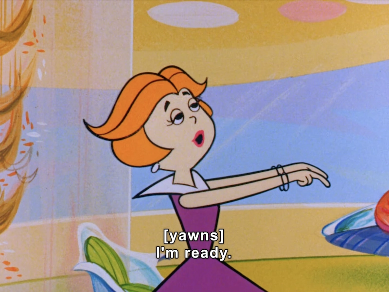 In this animated scene, a character with vibrant orange hair styled in soft waves appears to be yawning as she gestures with both hands, signaling her readiness for an activity. She is dressed in a purple dress with a contrasting collar. The background features a colorful, abstract design with curved shapes in shades of blue, yellow, and pastel tones, suggesting a playful and lighthearted atmosphere. The character’s expression reflects a mix of boredom and eagerness, encapsulated by her spoken words, “I’m ready.” This scene conveys a whimsical yet relatable moment, typical of classic animated series.