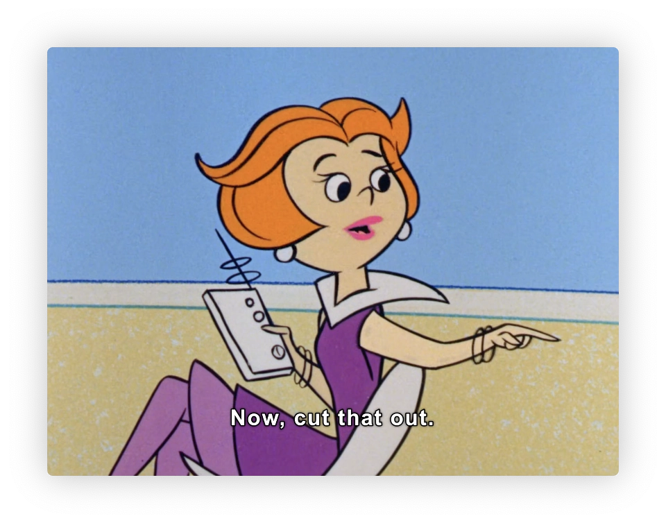 This is an image from an animated cartoon featuring a female character who has short orange hair and is dressed in a purple and white outfit. She is holding a small device with an antenna and is pointing with her right hand. There is text at the bottom of the image that says, "Now, cut that out." The background is simple with a light blue color that could portray the sky and a yellowish-brown which might be the ground or a sand area. The style and animation suggest that it could be from a mid-20th-century animated television show.