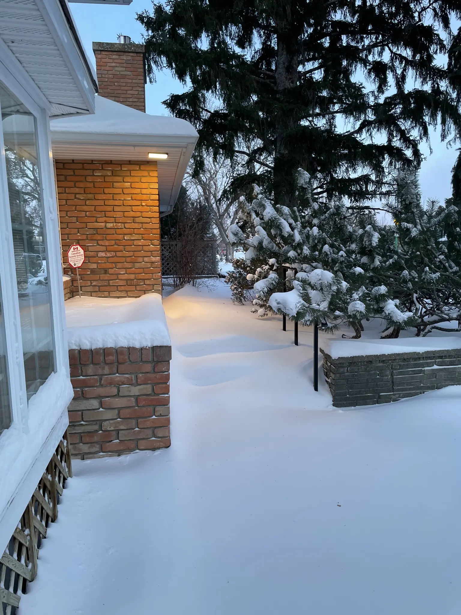 Snow drifts across the front of a house, burying the steps and more.