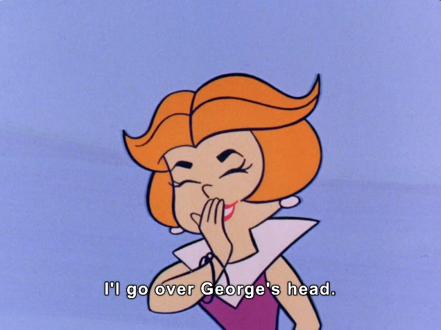 This image features a stylized animated character with vibrant orange hair and a playful expression. She is depicted with a charming smile, hand partially covering her mouth as if sharing a light-hearted secret. The character wears an elegant outfit, characterized by a white collar that frames her neck and shoulders, adding a touch of sophistication. The background is a simple, light blue, which helps to highlight the character's features and bright colors. The caption at the bottom reads, "I'll go over George's head," suggesting a humorous or cheeky context to the scene. The overall atmosphere is playful and whimsical, typical of classic animation styles.